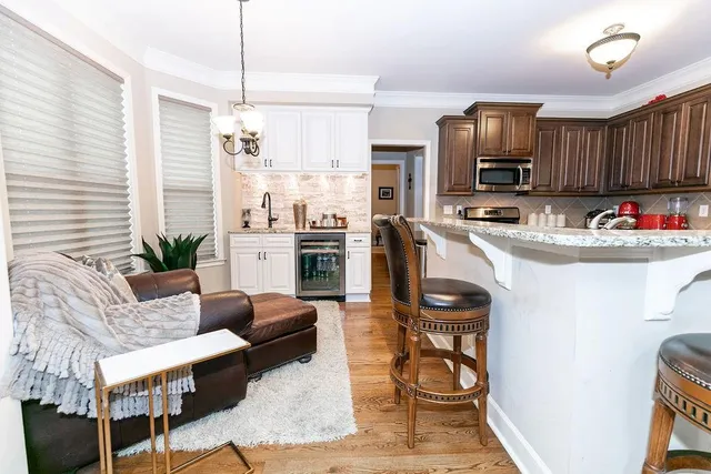 a kitchen with stainless steel appliances a stove a refrigerator a sink dishwasher a dining table and chairs with wooden floor