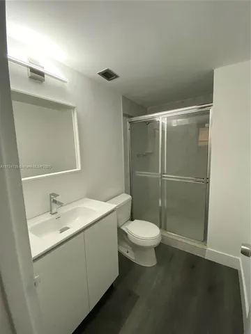 a white toilet sitting next to a bathroom sink and a mirror