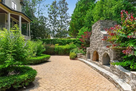 a pathway of a house with potted plants and a fountain