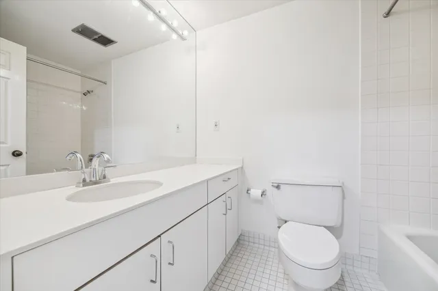 a bathroom with a granite countertop toilet sink and mirror