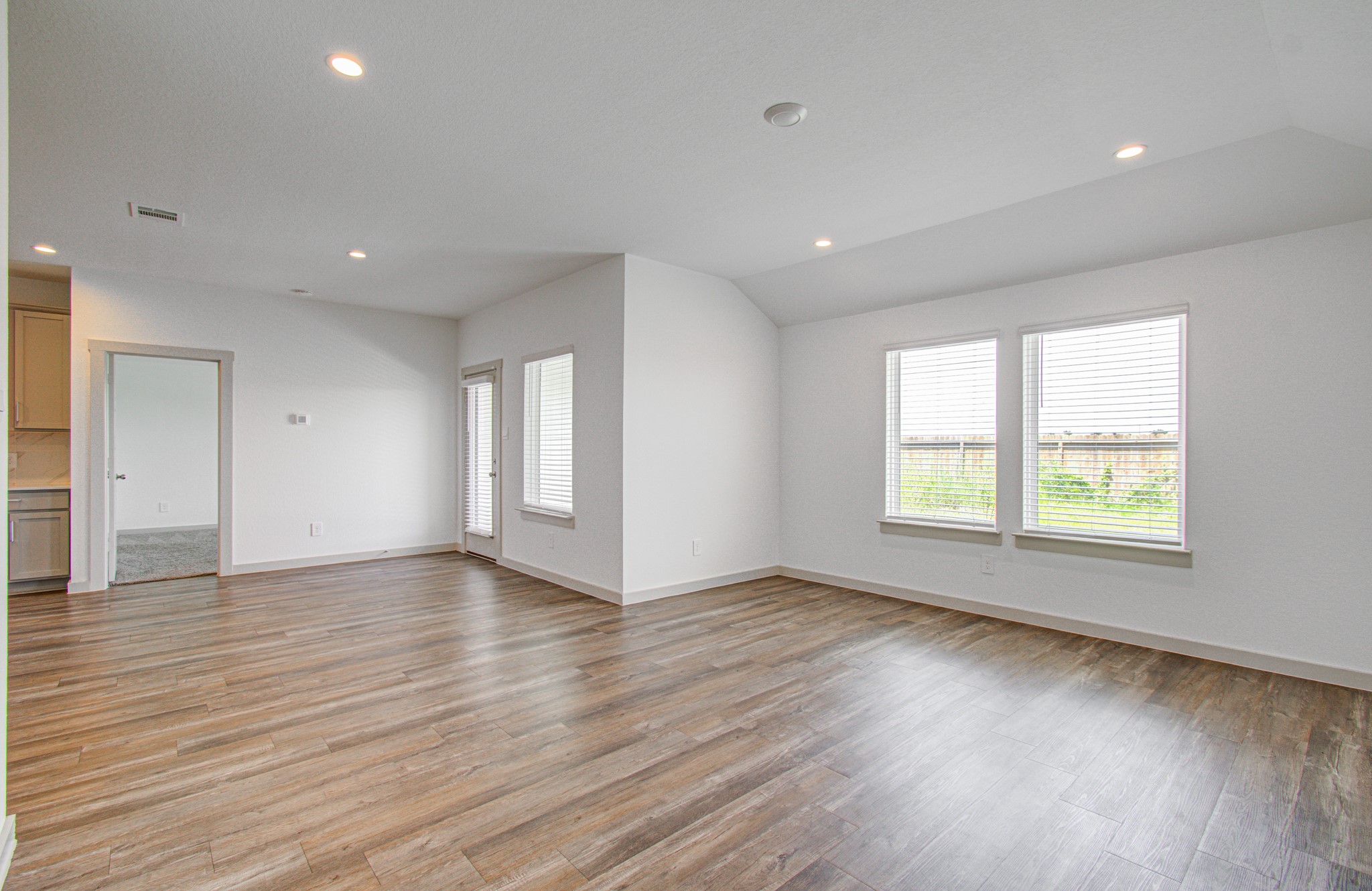 7903 Wrangler Shack Lane Rosharon, TX 77583 - Photo 22 of 29 This bright and spacious living area features modern wood flooring, recessed lighting, and large windows that flood the space with natural light, seamlessly connecting to adjacent rooms for versatile and comfortable living.