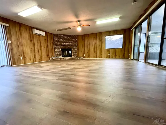 a view of an empty room with window and a kitchen