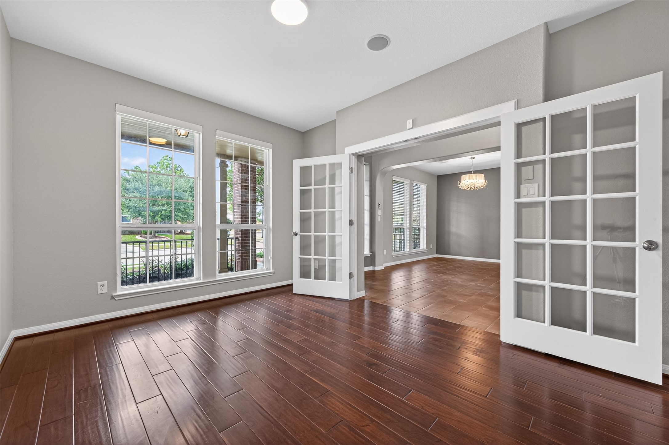 7003 Bristol Memorial Drive Spring, TX 77379 - Photo 14 of 40 Private office or study located near the front of this Spring TX 77379 home, featuring wood-look flooring, large windows for natural light, and French door entry. The front-facing placement offers separation from the main living areas while maintaining convenient access. Neutral finishes and clean lines create a versatile workspace ideal for remote work, planning, or flex use. Positioned in this spacious move-in ready home near The Woodlands, the study adds valuable functionality to the overall layout.