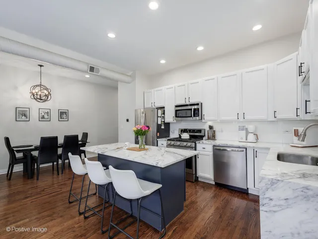 a kitchen with stainless steel appliances granite countertop a stove a sink dishwasher a stove a refrigerator with a dining table and chairs