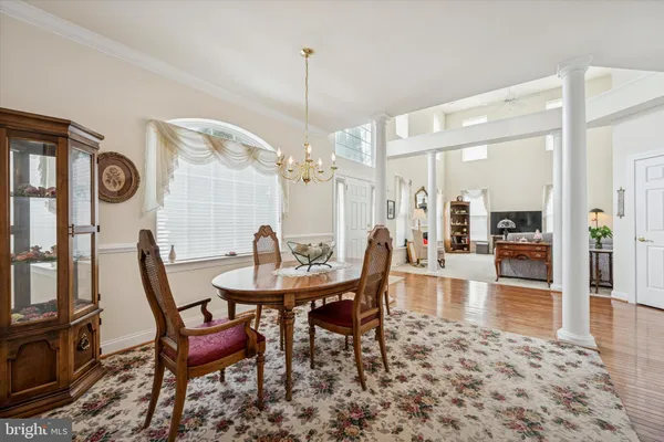 a view of a dining room and livingroom with furniture wooden floor a rug a fireplace and a chandelier