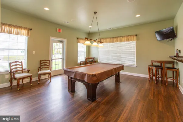 a room with wooden floor pool table and windows