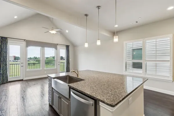 a kitchen with granite countertop a stove a sink and wooden floor