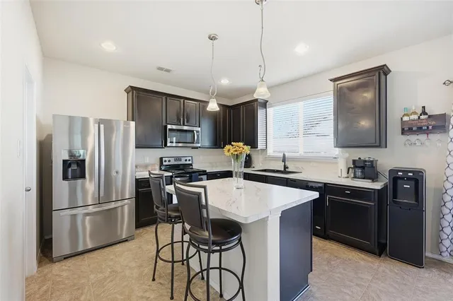a kitchen with stainless steel appliances a stove a sink a refrigerator a center island and chairs