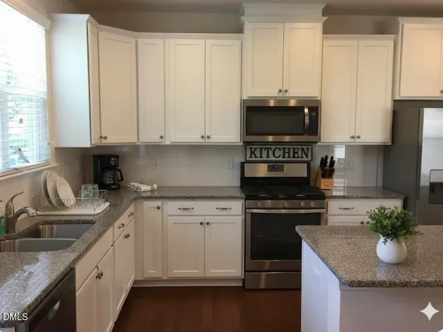 a kitchen with granite countertop a sink stove and cabinets