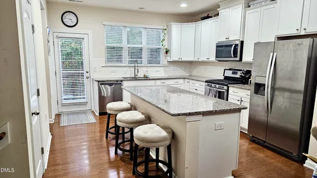 a kitchen with granite countertop a table chairs stove refrigerator and cabinets