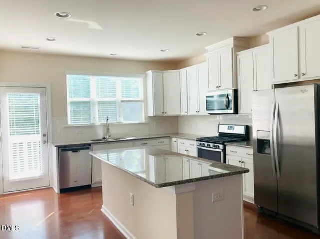 a kitchen with granite countertop a sink stove and refrigerator