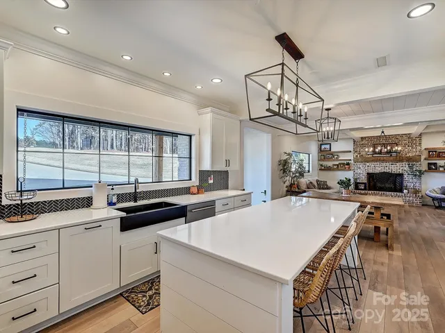 a kitchen with stainless steel appliances a stove a sink dishwasher and white cabinets with wooden floor