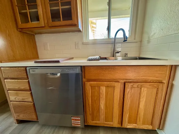 a view of a sink a window and cabinets