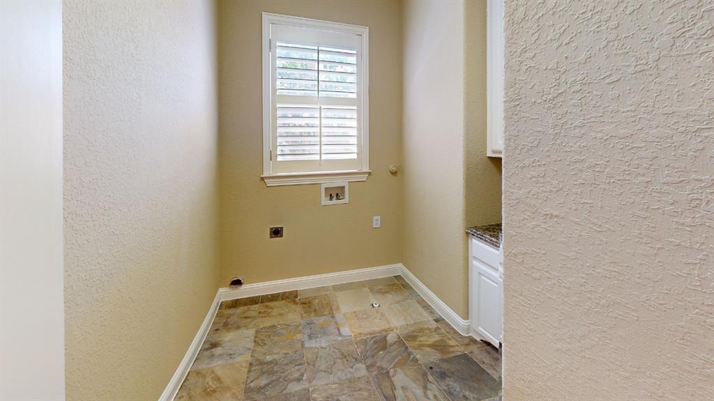 4516 Gilbert Avenue Dallas, TX 75219 - Photo 22 of 28 Laundry room featuring multi-toned tile flooring, a window with white louvered shutters, and a built-in cabinet with a granite-style countertop