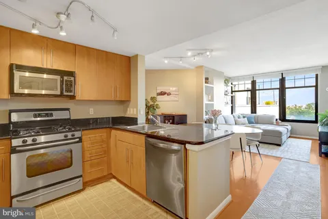 a kitchen with stainless steel appliances granite countertop a stove top oven a sink dishwasher a dining table and chairs with wooden floor