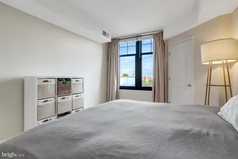 a bedroom with a bed dresser and a large window