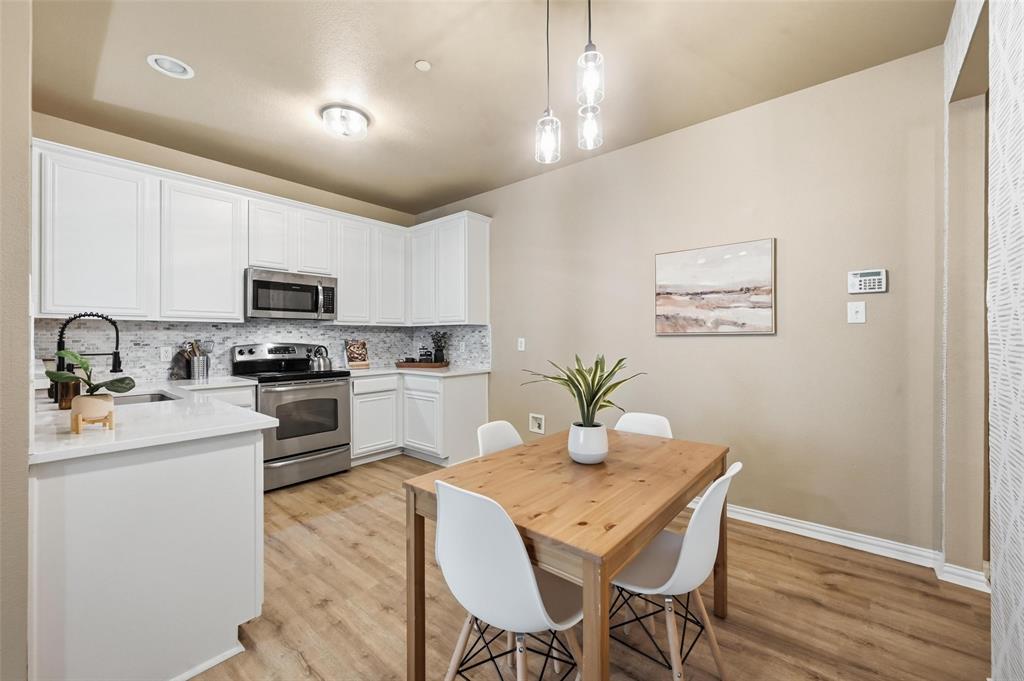 2522 Durango Ridge Drive Bedford, TX 76021 - Photo 6 of 35 Kitchen with stainless steel appliances, white cabinets, decorative light fixtures, and light wood-style flooring