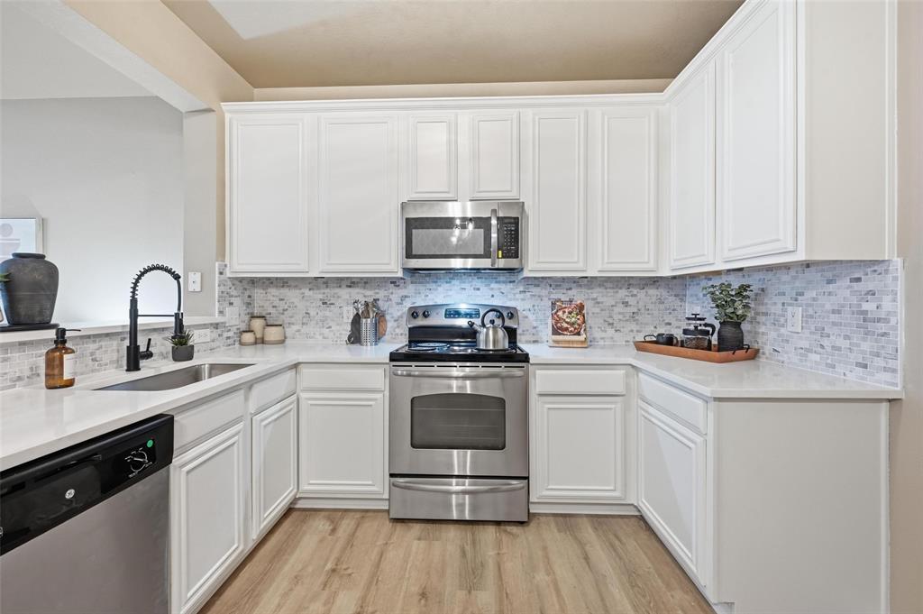2522 Durango Ridge Drive Bedford, TX 76021 - Photo 8 of 35 Kitchen featuring stainless steel appliances, white cabinetry, light stone countertops, and light wood-type flooring