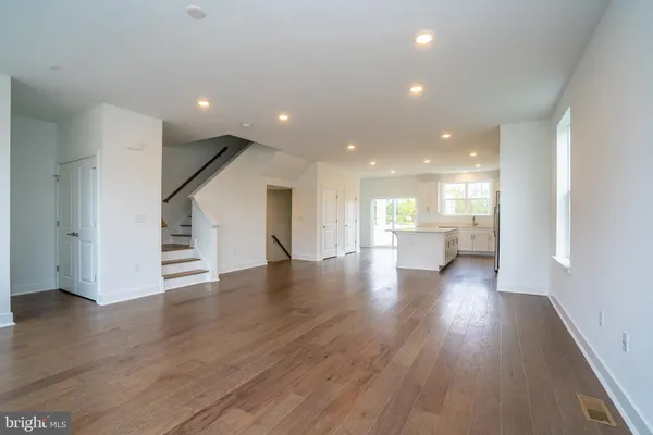 a view of a hallway with wooden floor and a kitchen
