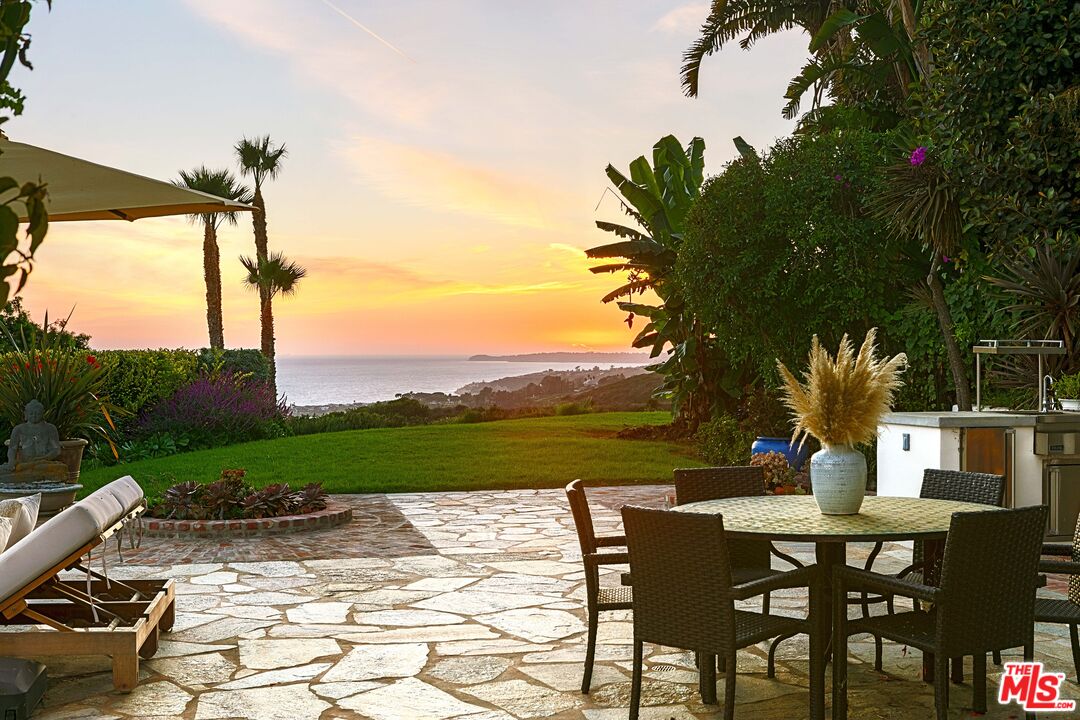 22355 Carbon Mesa Road Malibu, CA 90265 - Photo 14 of 69 a view of a patio with table and chairs potted plants with wooden floor and fence