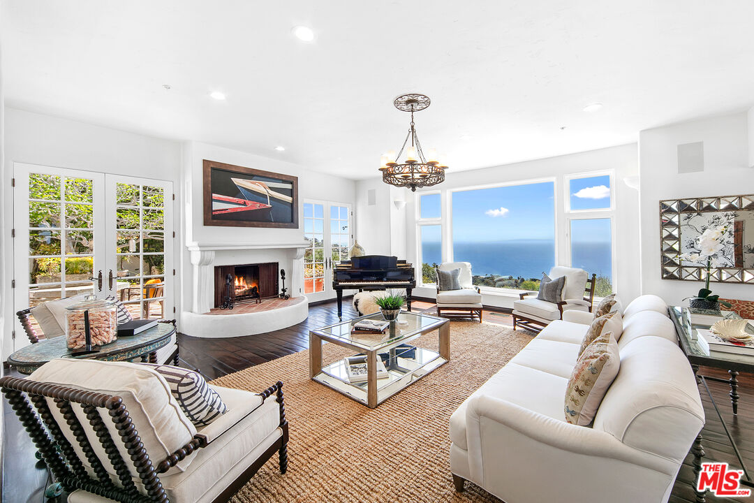22355 Carbon Mesa Road Malibu, CA 90265 - Photo 28 of 69 a living room with furniture a fireplace and a chandelier