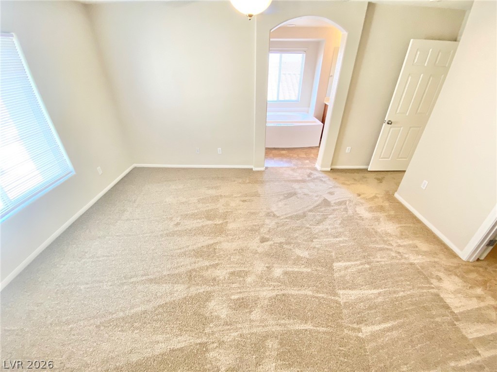 8569 Rhamus Court Las Vegas, NV 89149 - Photo 25 of 35 A spacious primary bedroom features soft carpeting, leading to a connected private bathroom with a soaking tub.
