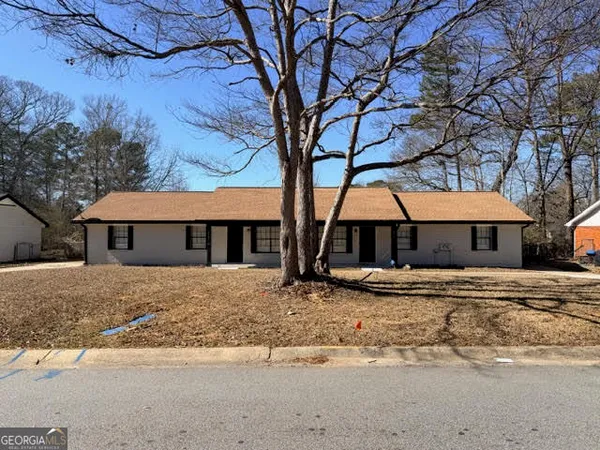 a big house with large trees and wooden fence
