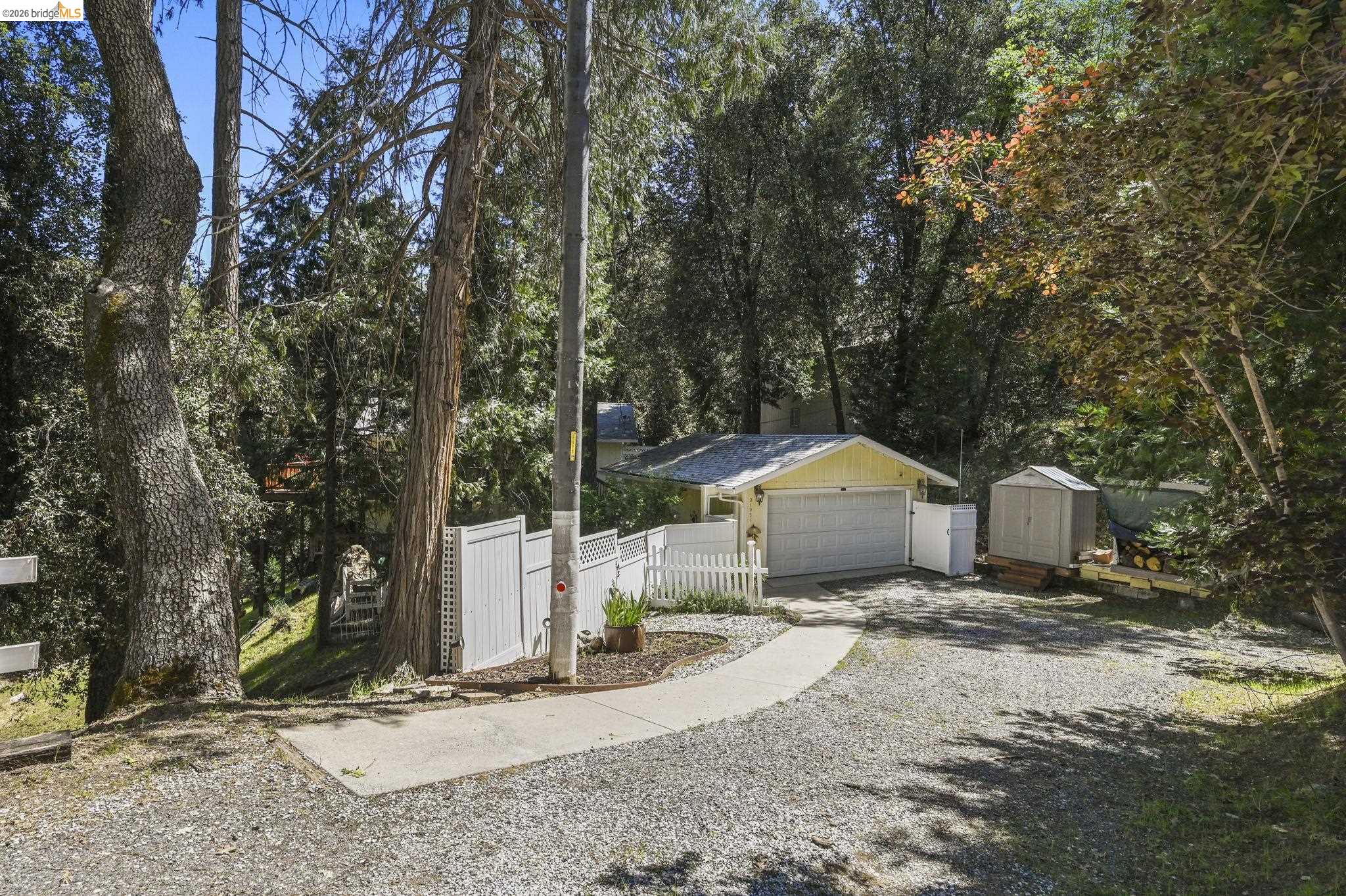 21931 Glenwood Road Sonora, CA 95370 - Photo 1 of 42 a front view of a house with a dirt yard and a large tree