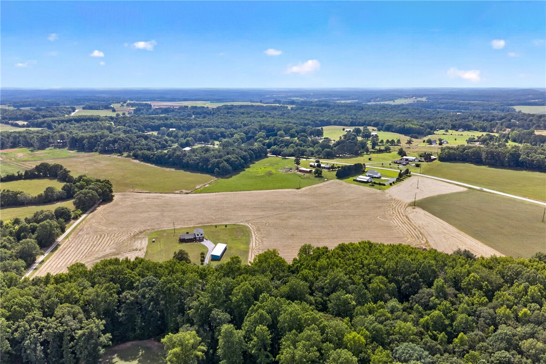 145 State Rd S-4-935 Pendleton, SC 29670 - Photo 2 of 10 An aerial panorama reveals a private home nestled amidst expansive farmland and mature woodlands.