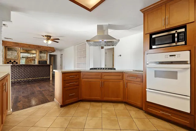 a view of a livingroom with wooden floor a ceiling fan and windows