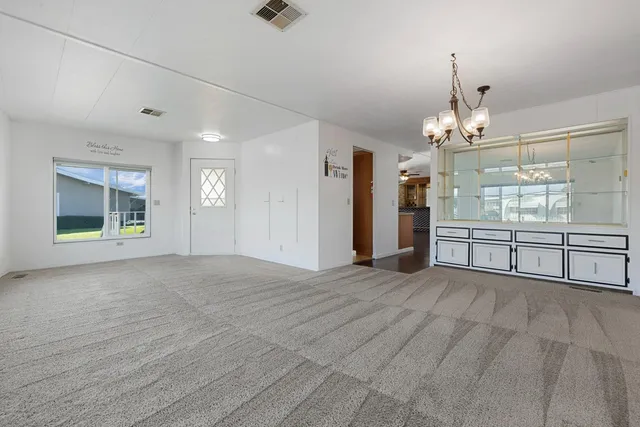 a view of an empty room with a window and kitchen view
