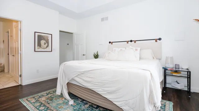 a large white bed in a bedroom next to a window