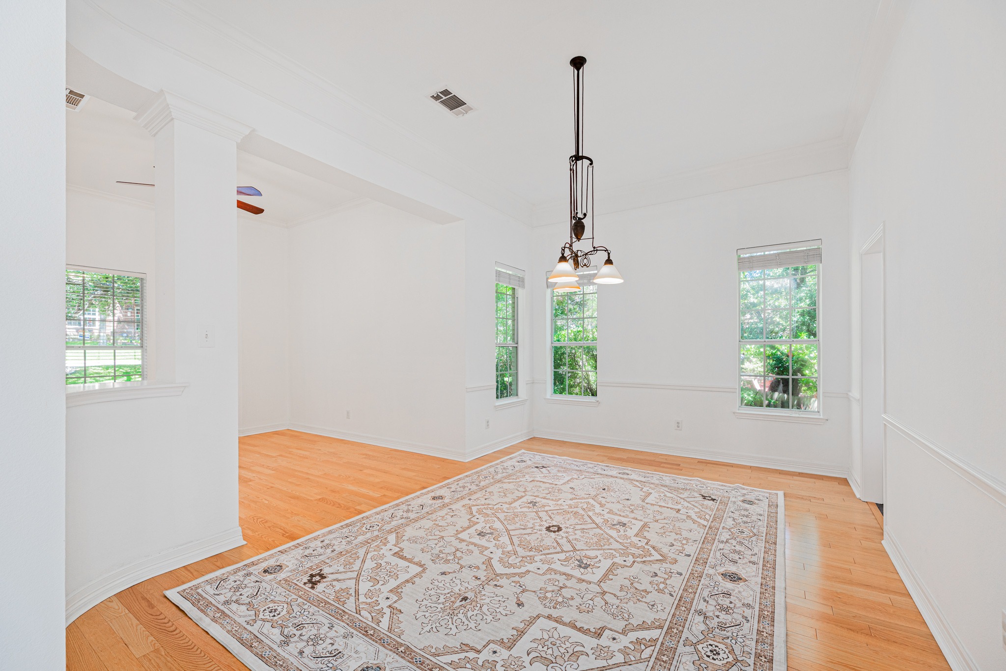 304 River Down Road Georgetown, TX 78628 - Photo 9 of 22 Spacious room featuring wood-finish flooring, multiple windows, a decorative ceiling fixture, and architectural columns