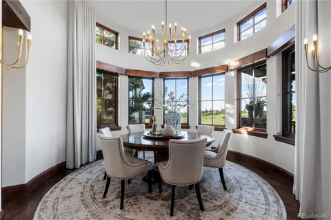 a dining room with wooden floor a chandelier a wooden table and chairs