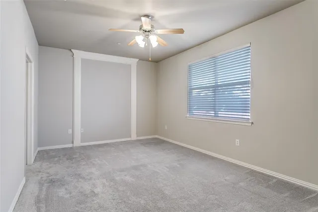 an empty room with windows and chandelier fan