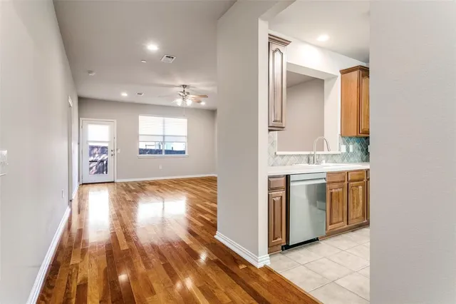 a view of a kitchen with a sink and dishwasher with wooden floor