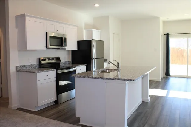 a kitchen with stainless steel appliances granite countertop a refrigerator stove a sink and a microwave