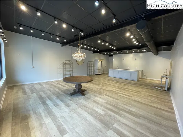 a view of an empty room with wooden floor and a fireplace