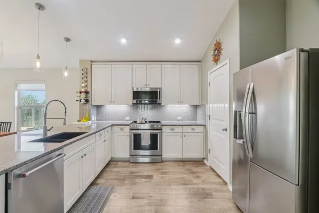 a kitchen with stainless steel appliances granite countertop a refrigerator sink and stove