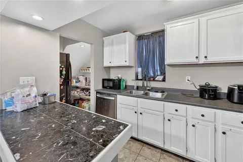 a kitchen with white cabinets and sink