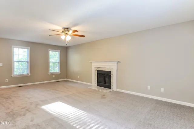 an empty room with windows and fireplace