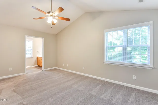 an empty room with chandelier fan and windows