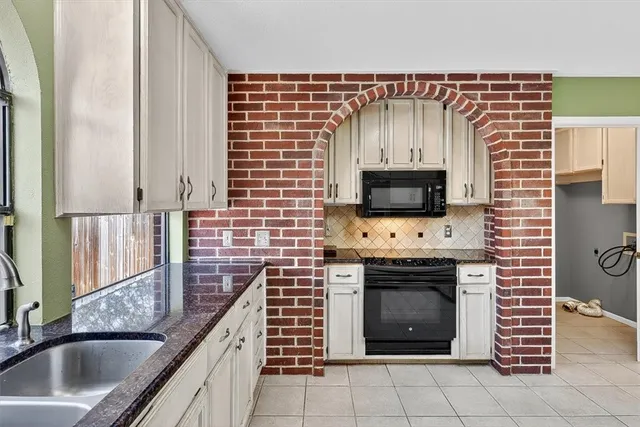 a kitchen with granite countertop a sink stove and microwave