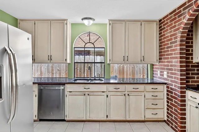 a kitchen with granite countertop white cabinets and a refrigerator
