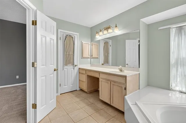 a spacious bathroom with a double vanity sink a mirror and a bathtub