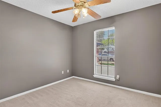 an empty room with windows and fan