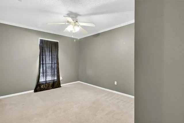 a view of an empty room with window and chandelier fan