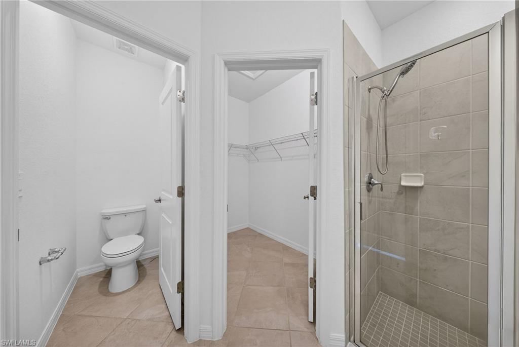 2224 Dragonfruit Way Naples, FL 34120 - Photo 12 of 33 Bathroom with a walk in closet, a stall shower, and light tile patterned floors