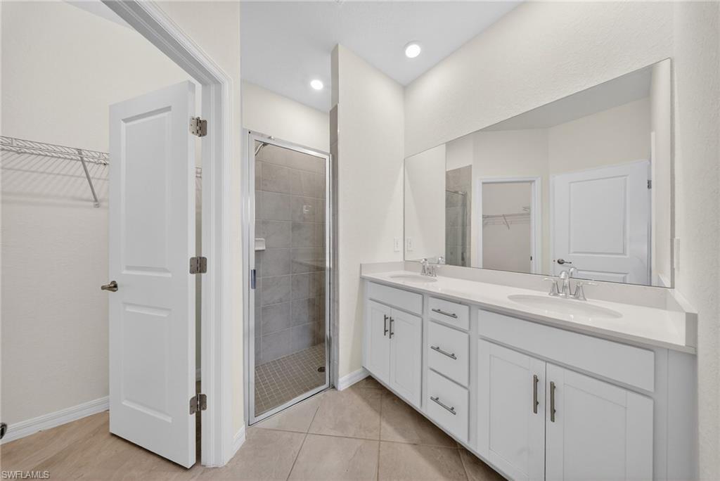 2224 Dragonfruit Way Naples, FL 34120 - Photo 13 of 33 Full bathroom with a walk in closet, double vanity, a stall shower, and light tile patterned floors