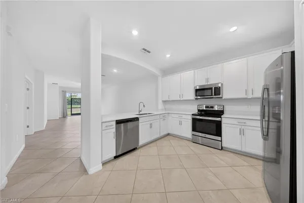 a kitchen with granite countertop a refrigerator and a stove top oven